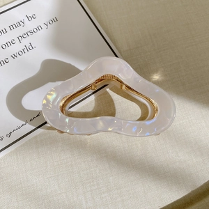 Macro detail of high-end acetate hair claw with white marble pattern and gold metal parts
