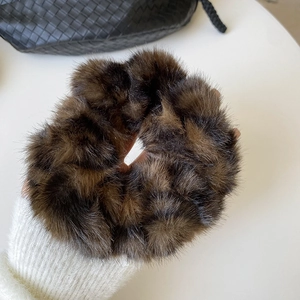 Chouchou en fausse fourrure marron foncé présenté au poignet avec pull en maille