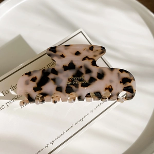 Detail of tortoise shell acetate hair claw with gold logo on an elegant display card