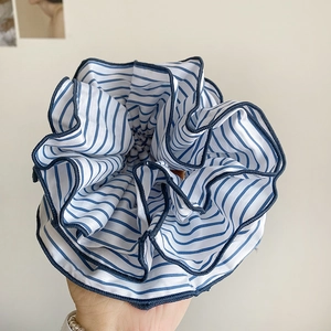 Detailed view of large blue and white striped fabric scrunchie with navy blue piping edges
