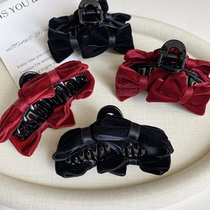 Detail of velvet bow hair claws in black and burgundy on a textured tray
