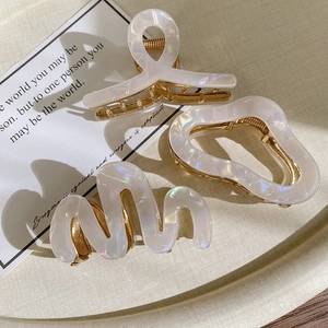 Three elegant acetate hair claws with pearlescent finish and gold metal teeth
