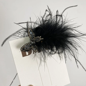 Gros plan sur une pince à cheveux en plumes noires avec ornements en strass papillon