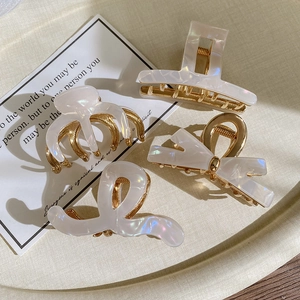 Detail of four-piece pearl white acetate hair claws with elegant gold metal base