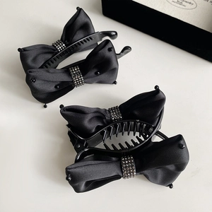 Detailed macro view of black satin bow banana clips with sparkling rhinestone accents