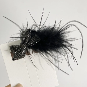 Détail de la pince à cheveux en plumes noires avec un nœud élégant en strass brillant