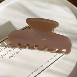Detailed side view of rose pink acetate hair claw clip with golden branding text