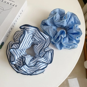 Detail shot of blue and white striped fabric scrunchies with pleated texture and soft edges