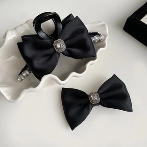 Detail view of black satin bow hair clips with luxury rhinestone and crystal embellishments