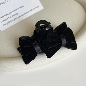 Detailed view of the soft black velvet bow hair claw clip on a textured tray