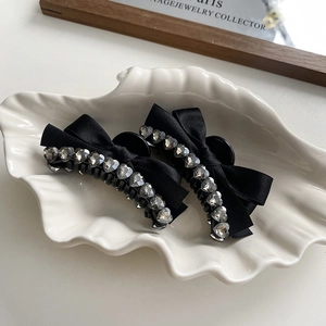 Detail of satin bow hair clips with heart-shaped rhinestone borders in a shell tray