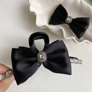Detail of black satin bow hair claw with a square diamond center and rhinestone accents