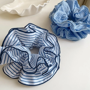 Close-up of blue and white striped fabric scrunchies on a shell tray for hair styling