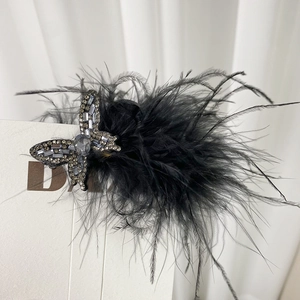 Détail de la pince à cheveux en plumes noires avec papillon argenté et strass blancs