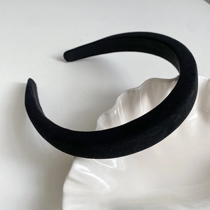 Détail d'un serre-tête en velours noir rembourré avec une texture douce sur un plateau