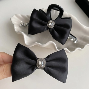 Elegant black satin bow hair clip with crystal rhinestone center for luxury hair styling