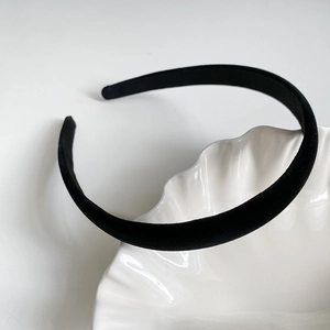 Gros plan d'un serre-tête en velours noir posé sur une assiette décorative en porcelaine
