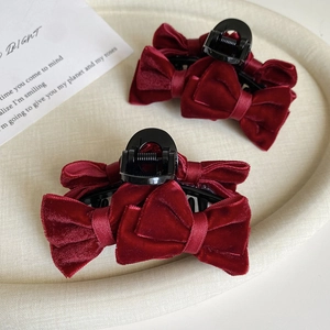 Close-up of two dark red velvet bow hair claws showing delicate fabric texture and grip