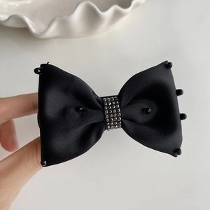 Close-up of black satin bow hair clip with sparkling rhinestones and beaded details