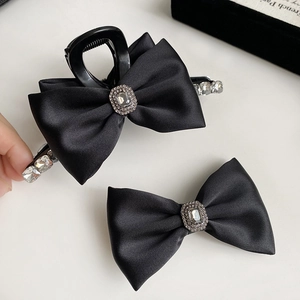 Detailed view of black satin bow hair clip with luxury rhinestone centerpiece and crystals