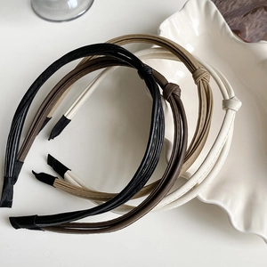 Detail of twisted faux leather headbands in black, coffee, beige, and white colors