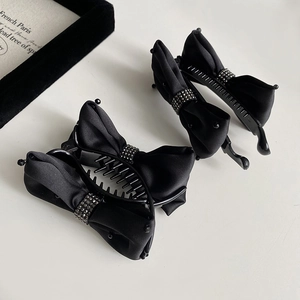 Detailed view of matte black bow banana hair clips with sparkling rhinestone center