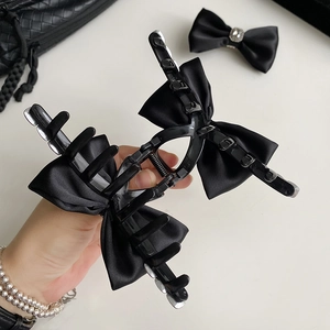 Close-up of elegant black satin bow hair claw clip featuring polished plastic and metal spring