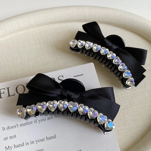 Close-up of black satin ribbon hair claw clips with sparkling heart-shaped rhinestones