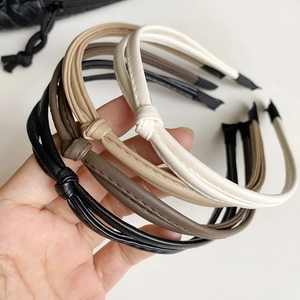 Detail of four textured PU leather knotted headbands in black, coffee, khaki and cream white