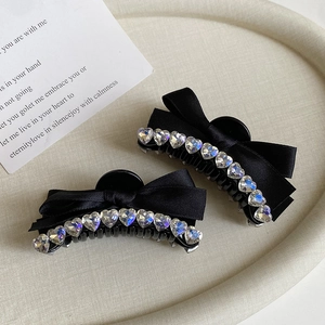 Detail of elegant black ribbon bow hair clips with sparkling heart-shaped crystal accents
