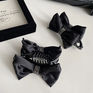Detail of black satin bow banana hair clips with sparkling rhinestone center ornaments