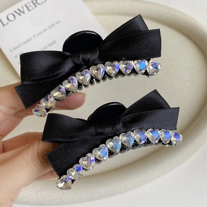Close-up of black ribbon bow hair clips with heart-shaped rhinestones and crystal detail