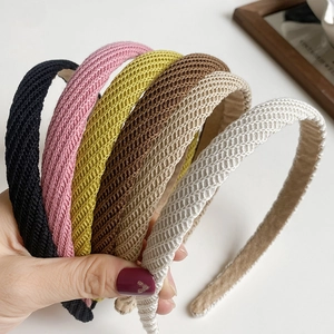 Détail de divers serre-têtes en tricot aux couleurs noir, rose, jaune, marron et beige