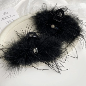 Detail view of black feather hair claw clips with faux pearls and sparkling gemstones