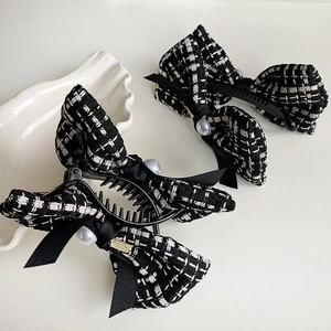 Detail view of tweed houndstooth hair clips with silk bows and pearl embellishments