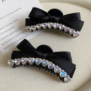 Detail of two black satin ribbon hair clips with sparkling rhinestone heart borders