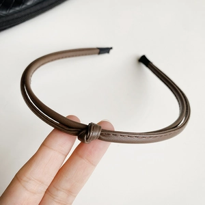 Detail of a brown leather-textured headband with a double-strand knot design and anti-slip tips