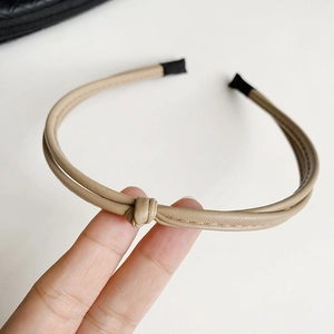 Detail of khaki leather knotted headband with dual strands and visible stitching