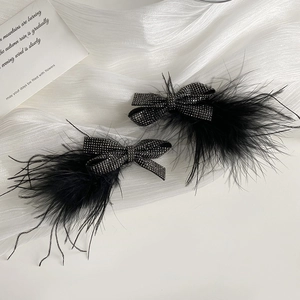 Macro detail of black ostrich feather hair clips with shimmering rhinestone bows