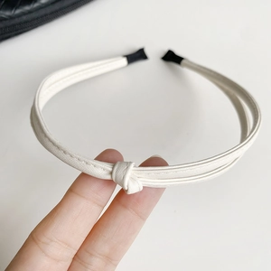 Close-up of cream white faux leather headband featuring a minimalist knot detail