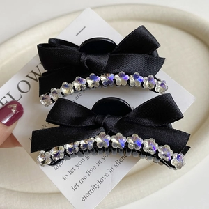 Macro detail of black satin bow hair clips featuring floral crystal rhinestone accents