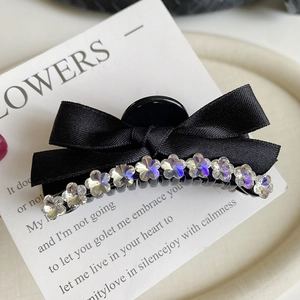 Close-up of black ribbon bow hair claw with iridescent crystal flower rhinestones