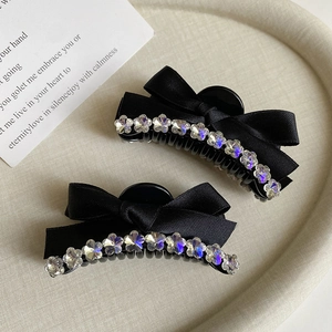 Detail of elegant black ribbon bow hair clips with sparkling rhinestone flower edging