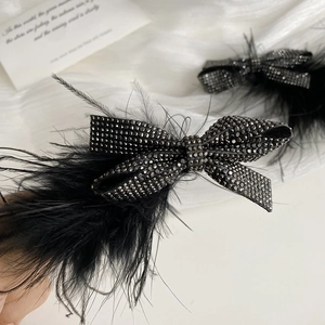 Elegant black ostrich feather hair clip featuring sparkling rhinestones and a stylish bow