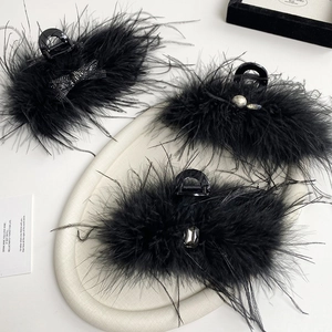 Three black feather hair claws with rhinestones, pearls, and crystals on a white tray