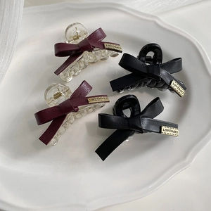 Set di quattro fermagli per capelli in pelle con fiocco rosso scuro e nero su vassoio