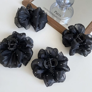 Detailed view of four black chiffon flower claw clips with elegant white polka dots