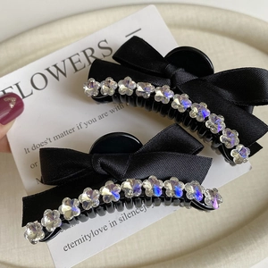 Detail of black ribbon bow hair claws with sparkling rhinestone floral accents on a card