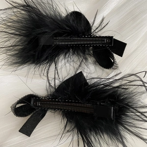 Elegant pair of black ostrich feather hair clips with sparkling rhinestone bow details