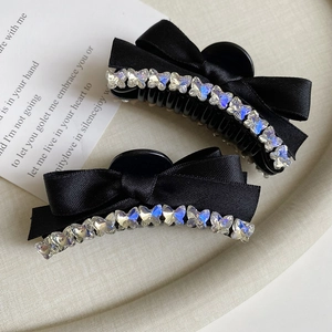 Close-up of black ribbon bow hair clips with shimmering rhinestone butterfly details
